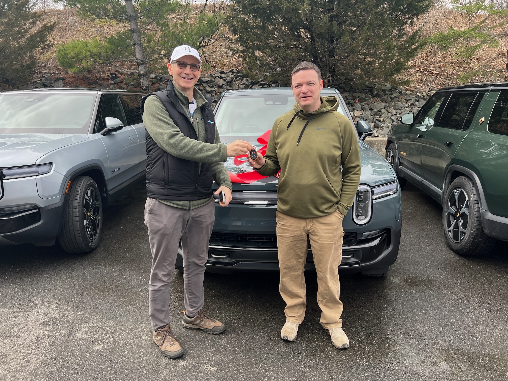 Two men shaking hands in front of Rivian R1T.