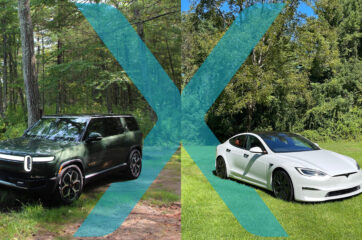 Two cars in a grassy field with trees in the background. A green Rivian R1S on the left and a white Tesla Model X on the right.